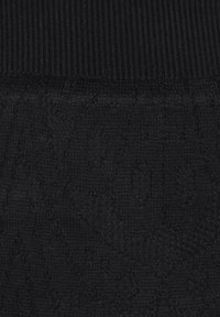 Svart stickad tyg har en ribbad textur upptill och ett mönster av subtila, intrikata designer genom den nedre delen.