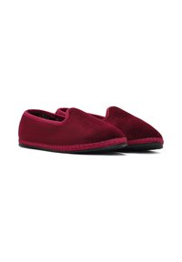 Une paire de chaussons en suede rouge foncé, à enfiler, avec des semelles noires et des coutures visibles le long du bord, présentée côte à côte sur un fond blanc.