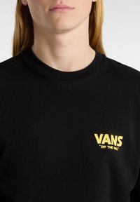Czarna bawełniana koszulka z żółtym logo "VANS" oraz napisem "OFF THE WALL" na lewej piersi; krótki rękaw, okrągły dekolt.