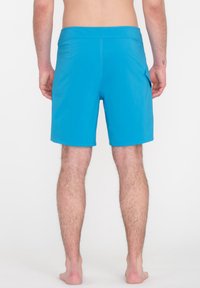 Blaue Badehosen mit glatter Textur, in mittellanger Länge bis zum Oberschenkel, elastischem Bund und seitlichen Taschen, die von der Rückansicht sichtbar sind.
