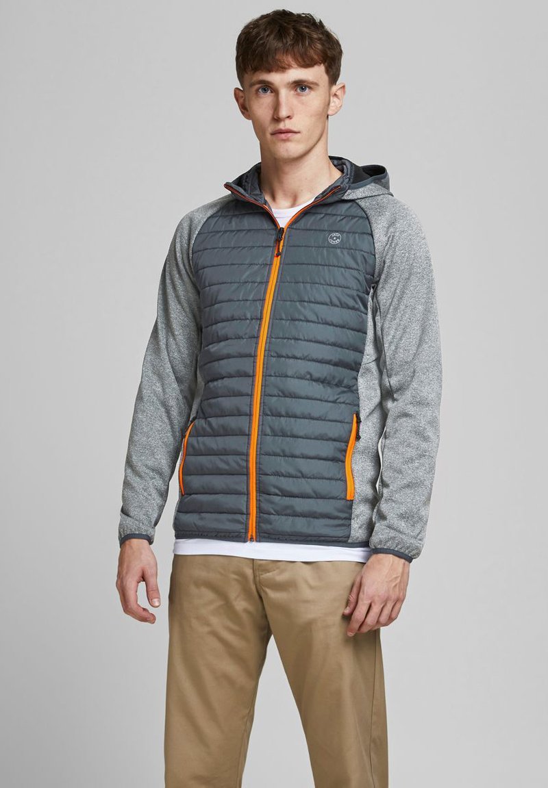 Graue gesteppte Jacke mit orangefarbenem Reißverschluss und Akzenten; graue Ärmel aus strukturiertem Stoff; taillierte Passform; mit Kapuze.