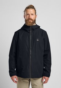 Sort vandtæt jakke med hætte, fuld frontlynlås, elastiske manchetter og et brystlogo. Glat tekstur, afslappet pasform, minimalistisk design.