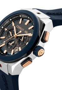 El reloj CERRUTI 1881 presenta una esfera redonda de color negro, manecillas en tono dorado, subesferas, una correa de silicona azul y una caja plateada con acentos en oro rosa.