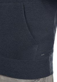 Felpa con cappuccio blu scuro caratterizzata da una tasca frontale a marsupio, tessuto texture e orlo a costine. Include un piccolo etichetta del marchio sul lato inferiore.