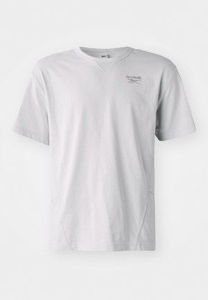 T-shirt à manches courtes gris clair en tissu doux ; présente un col rond et un logo Reebok discret sur la poitrine. Design simple, sans motifs.