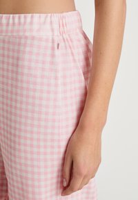 Roze en witte geruite stoffen broek met een elastische tailleband en zijzakken. De stof lijkt zacht en lichtgewicht te zijn.