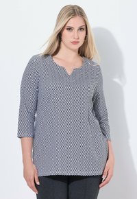 Zwart-wit zigzagpatroon top met een V-hals, 3/4 mouwen en een losse fit. Lichtgewicht stof met een gladde textuur.