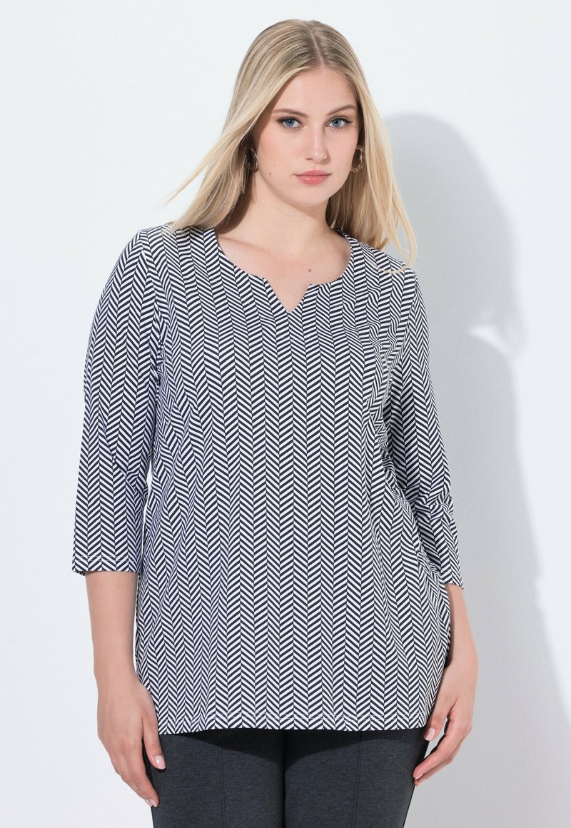 Zwart-wit zigzagpatroon top met een V-hals, 3/4 mouwen en een losse fit. Lichtgewicht stof met een gladde textuur.
