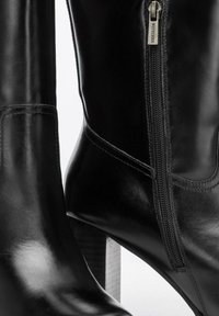 Czarne skórzane botki z gładką fakturą, wyposażone w boczny zamek błyskawiczny i wąski, sztaplowany obcas. Minimalistyczny design i smukła sylwetka.