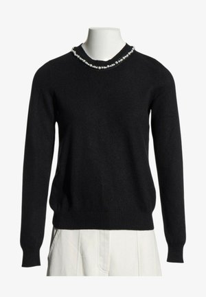 Pull noir à manches longues avec détail de perles autour de l'encolure ronde, présenté sur un buste de mannequin blanc avec pantalon blanc.