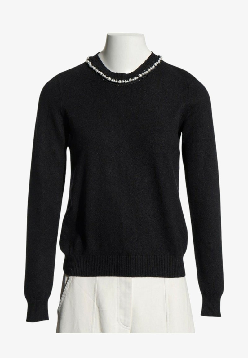 Pull noir à manches longues avec détail de perles autour de l'encolure ronde, présenté sur un buste de mannequin blanc avec pantalon blanc.