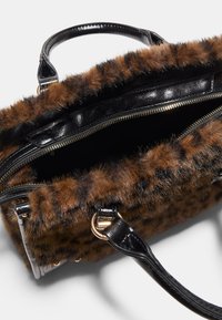 Borsa in pelliccia sintetica con stampa animale marrone, dettagli in pelle nera, chiusura con zip superiore e doppie maniglie. L'interno presenta una tasca con zip.