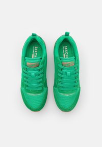 Zapatillas deportivas verdes con parte superior de malla y ante, punta redonda, cordones planos y suela de goma. Presenta el logo de Skechers en la lengüeta.