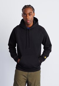 Zwarte hoodie met een trekkoordcapuchon, kangoeroezak en geribbelde cuffs. Voorzien van een klein logo op de linker mouw. Casual, losse pasvorm.