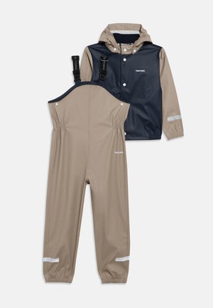 Σετ αδιάβροχης βροχής δύο τεμαχίων με σχέδιο σε μπλε ναυτικό και μπεζ, με ανακλαστικές λεπτομέρειες, ελαστικές μανσέτες και ρυθμιζόμενα τιράντες.