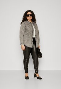 Gray denim shirt with button-down front, black faux leather leggings, black block-heeled shoes, and a black sequined bag.