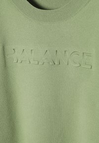 Suéter verde de algodón con cuello acanalado y texto en relieve "BALANCE" en la parte frontal con un acabado suave y mate.
