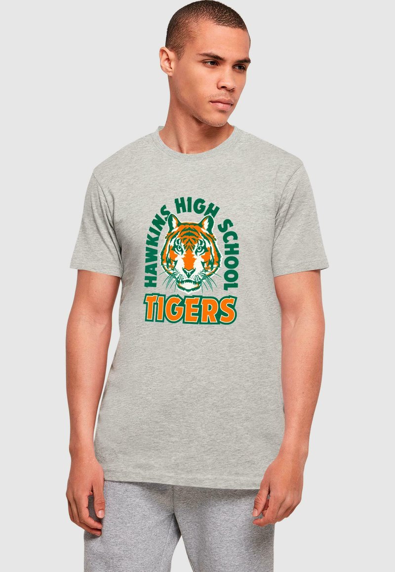 Graues Baumwoll-T-Shirt mit einem großen orangenen Tiger-Graphic, darüber in Grün "HAWKINS HIGH SCHOOL" und darunter in Orange "TIGERS".