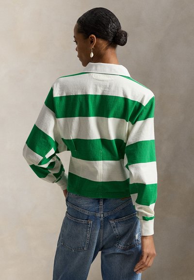 Μπλούζα ράγκμπι από βαμβάκι με έντονες οριζόντιες ρίγες σε πράσινο και άσπρο, γιακά και άνετη εφαρμογή, σε συνδυασμό με τζιν παντελόνι με ψηλή μέση.