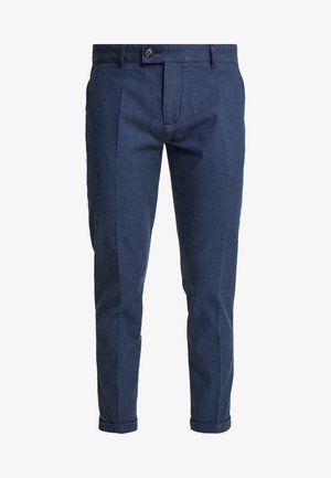 Pantaloni di cotone blu navy con una vestibilità su misura, dotati di pieghe frontali, chiusura con bottone e risvolti. Il tessuto testurizzato aggiunge interesse visivo.