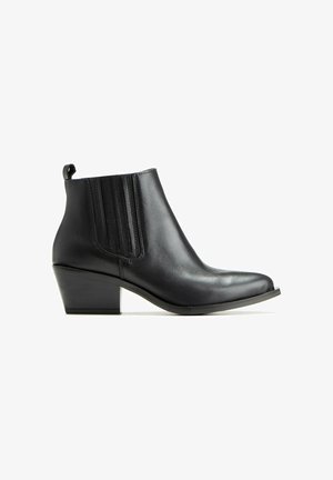 Bottines noires en cuir avec un bout pointu, un talon bas en empilage, des accents de couture verticale et une boucle à l'arrière pour un enfilage facile.