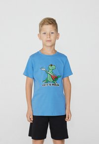 Blaues Kurzarm-Cotton-T-Shirt mit einem Cartoon-Dinosaurier in Sonnenbrille, der eine rote Gitarre spielt. Der Text lautet "LET'S ROCK". Kombiniert mit schwarzen Shorts.