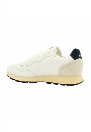Sneaker bianca con pelle perforata, suola intermedia in crema morbida e suola nera. Presenta un accento blu navy sul tallone con dettaglio in rilievo "1979".