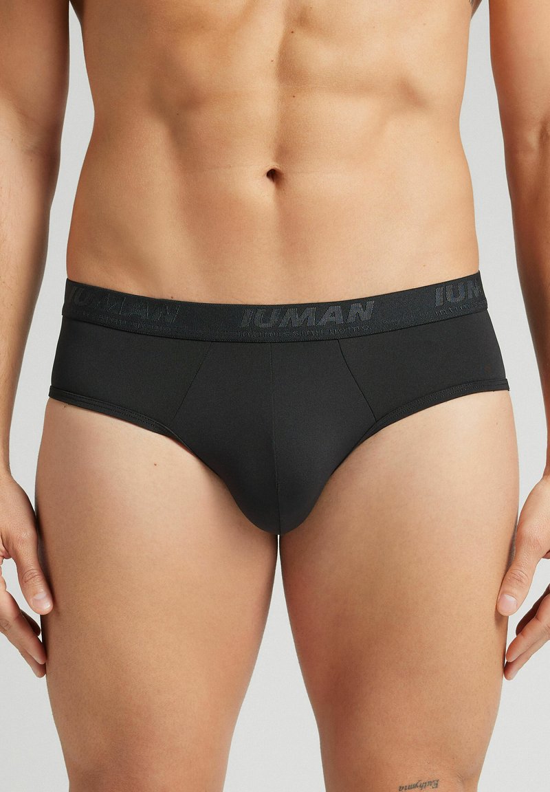 Bóxer negro con una cinturilla ancha que presenta texto en relieve. El material parece suave, con un diseño ajustado y detalles de costura mínimos.