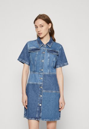 Denim-paitakleid mit kurzen Ärmeln, Knopfleiste und zwei Brusttaschen. Es zeichnet sich durch ein Patchwork-Design in verschiedenen Blautönen und einen spitzen Kragen aus.