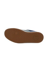 Sneaker with a navy textured upper, white logo, and a rubber brown outsole featuring a patterned grip. Distinct round emblem near the heel.