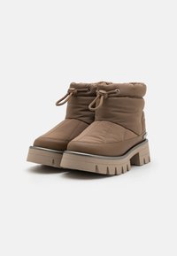 Bottes cheville marron matelassées avec une fermeture à cordon, des semelles épaisses compensées et une tige rembourrée pour le confort et la chaleur.