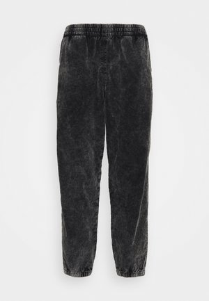 Zwarte corduroy broek met een elastische tailleband, tapered fit en ribbelstructuur. Beschikt over een zachte, fluweelachtige uitstraling.