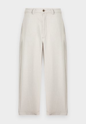 Fehérsárga, magas derekú, széles szárú nadrág gombos és cipzáras rögzítéssel, övbújtatókkal és látható varrási részletekkel, egyszínű háttéren.