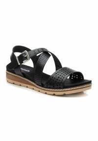 Sandalias de cuero negro con correas perforadas, hebilla ajustable, suela plana y acentos en tono marrón claro. Diseñadas con una plantilla acolchada para mayor comodidad.