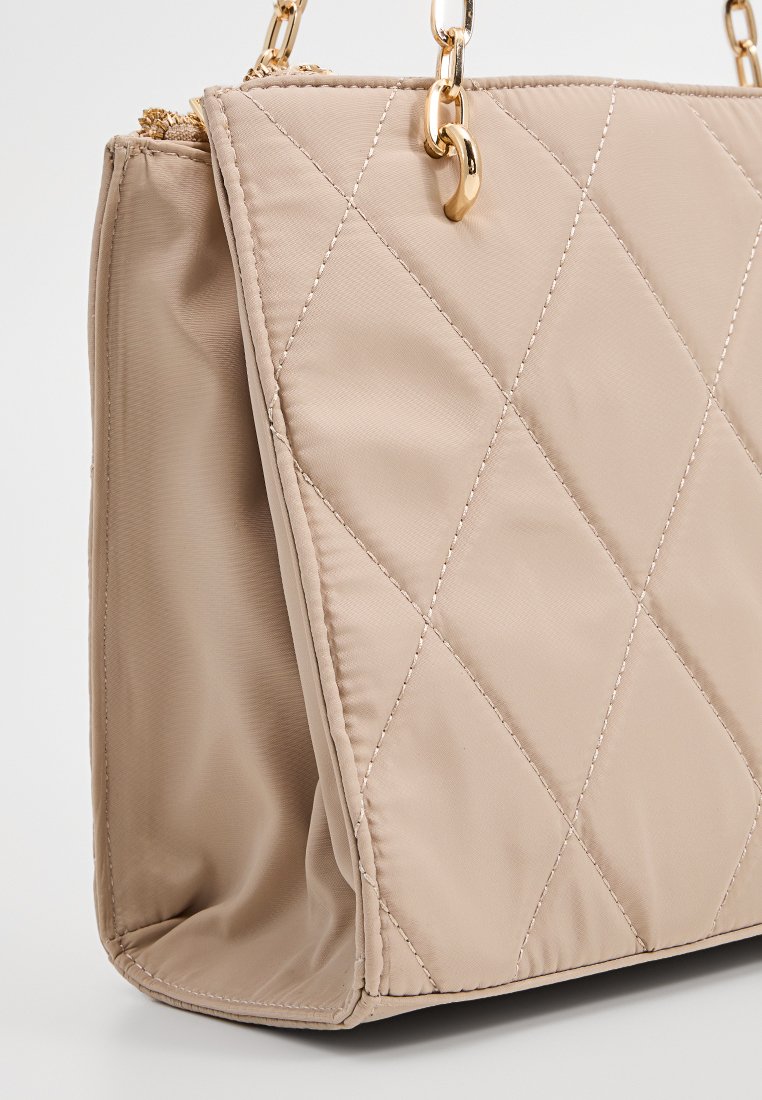 Sac à main matelassé beige avec quincaillerie dorée, présentant une texture lisse, une bandoulière en chaîne et un motif en diamant sur l'extérieur.
