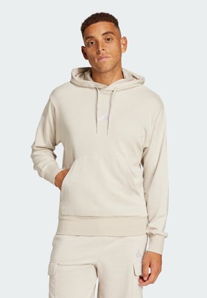 Felpa leggera beige realizzata in tessuto morbido, con una tasca frontale a canguro, cappuccio con cordino e piccolo logo sul petto.