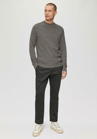 Grijze gebreide trui met een ronde hals, gecombineerd met donker gestreepte broeken en beige sneakers. Eenvoudige esthetiek met zachte texturen.