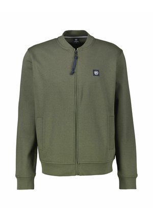 Olivengrøn lynlåsjakke med ståkrave, to sidelommer og et lille logo-patch på venstre bryst. Stoffet virker glat og blødt.