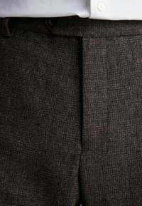 Dunkelgraue Hose aus strukturiertem Stoff, mit einem einzelnen vorderen Falten, Haken- und Knopfverschluss sowie einem Bund mit Gürtelschlaufen.