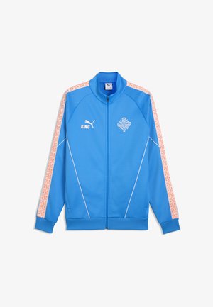 Niebieska kurtka Puma na zamek z białym logo, napisem "KING" na lewej piersi, wzorzyste pomarańczowo-białe paski na rękawach oraz białe przeszycia.