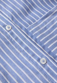 Camicia a righe azzurro chiaro realizzata in tessuto dalla superficie liscia, con strisce orizzontali bianche e chiusura con bottoni.