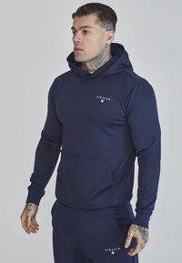 Navy blue hooded sweatshirt made of soft fabric, featuring a front pocket and a small white logo on the chest. Fitted design with long sleeves.