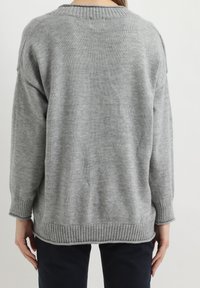 Suéter gris de punto con un corte relajado, cuello y dobladillo de canalé, y mangas largas. Textura suave y diseño sencillo, sin patrones visibles.