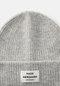 Beaniem grigio a maglia realizzato in morbido lana. Presenta una texture a costine e un risvolto con un'etichetta bianca che mostra "MADS NØRGAAARD COPENHAGEN."