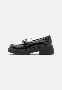 Zwarte lakleren loafers met een witte schacht, voorzien van een gouden gesp detail en een dikke zwarte gestructureerde plateauzool.