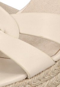 Sandalias de esparto beige con correas anchas entrelazadas hechas de material suave, con una suela de cuña envuelta en yute para añadir textura.