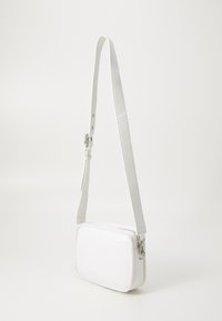 Bolso blanco rectangular bandolera hecho de cuero suave, con cierre de cremallera y una correa ajustable. Diseño minimalista con herrajes plateados.