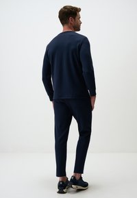 Felpa blu navy e set di pantaloni coordinati, in morbido materiale, con scollatura a girocollo, polsini a costine, vestibilità slim, con tasche laterali nei pantaloni.