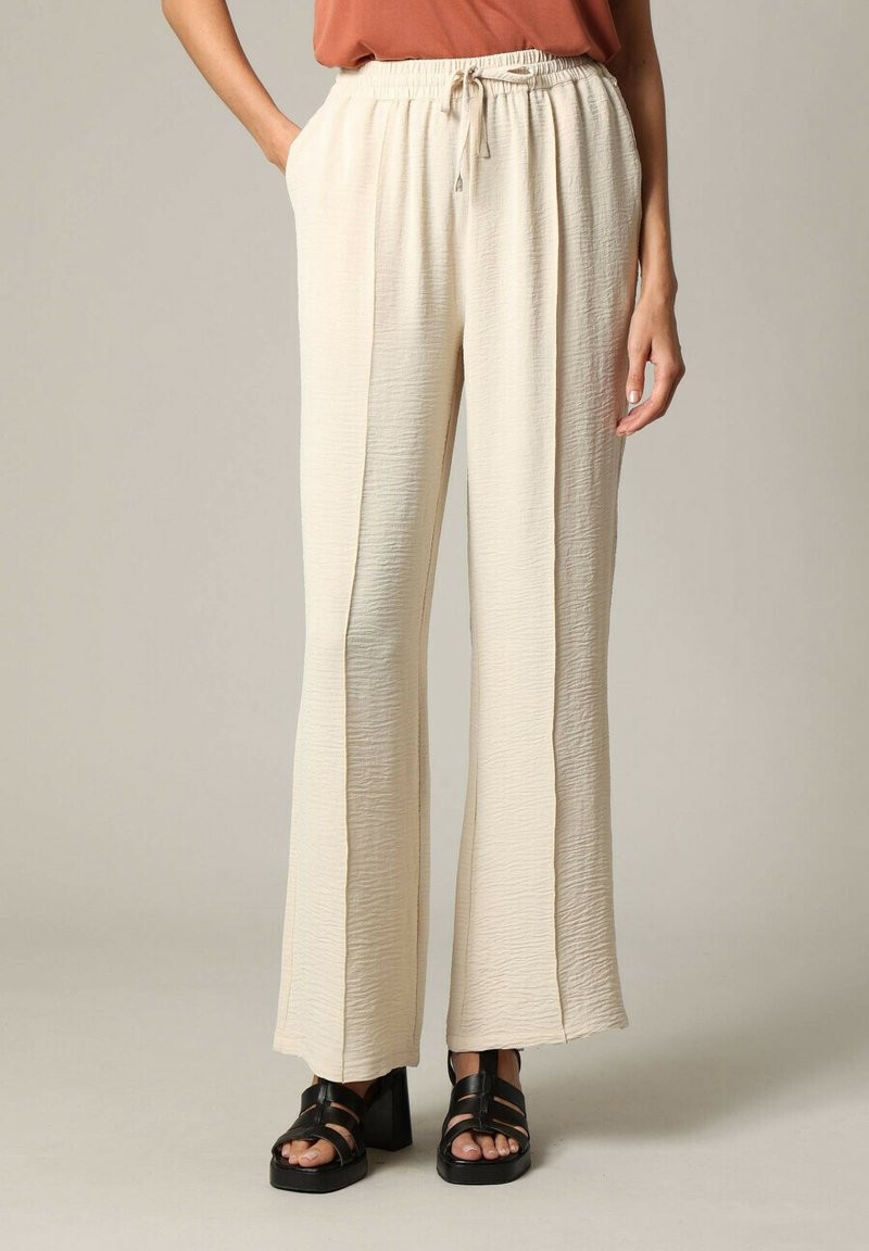 Lichtbeige wijde pantalon van gestructureerde stof, voorzien van een elastische tailleband met een trekkoord en zijzakken.