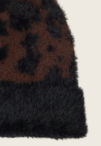 Braun- und schwarz texturierte Strickmütze mit einer flauschigen Oberfläche, die ein Leopardenmuster in dunkelbraun und einen einfarbigen schwarzen Bund aufweist.